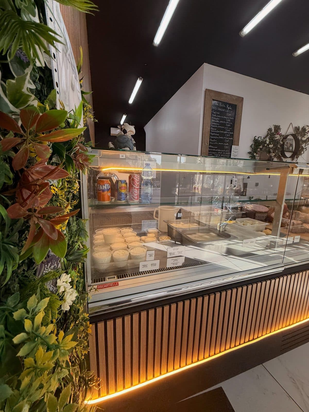 Le mur végétal au premier plan, et derrière lui la vitrine des laitiers frais sous le bardage de bois